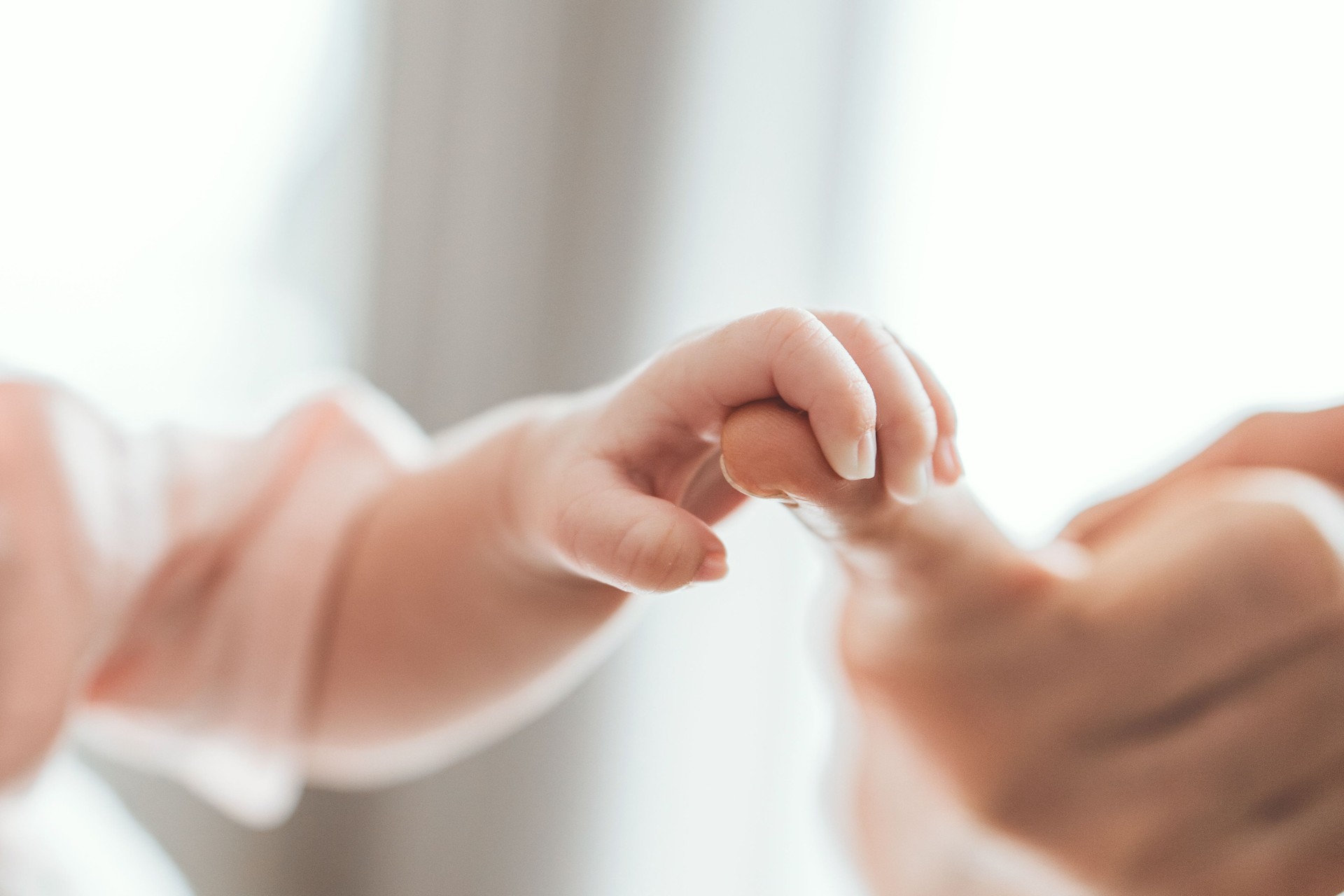 Newborn baby holding her mother's finger. Concept of child care, feeling safe, Healthcare, parent love.